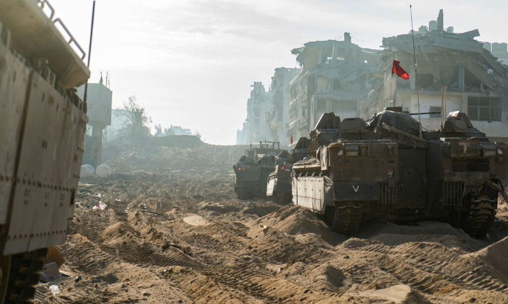 A view shows Israeli military vehicles next to damaged buildings amid the ongoing ground operation of the Israeli army against the Palestinian Islamist group Hamas, in the Gaza Strip, in this handout image released November 18, 2023. Israel Defense Forces/Handout via REUTERS THIS IMAGE HAS BEEN SUPPLIED BY A THIRD PARTY
