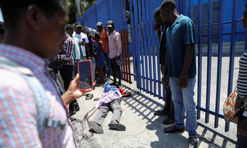 As pessoas olham para o corpo de um homem morto enquanto gangues rivais disputam o controle do território enquanto o estado permanece em grande parte ausente, em Porto Príncipe, Haiti 1º de abril de 2024. REUTERS/Ralph Tedy Erol