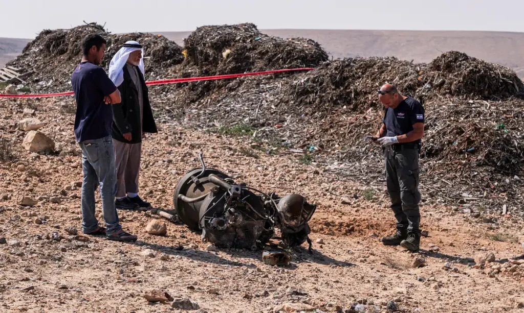 A police officer and residents inspect the remains of a rocket booster that, according to Israeli authorities critically injured a 7-year-old girl, after Iran launched drones and missiles towards Israel, near Arad, Israel, April 14, 2024. REUTERS/Christophe van der Perre