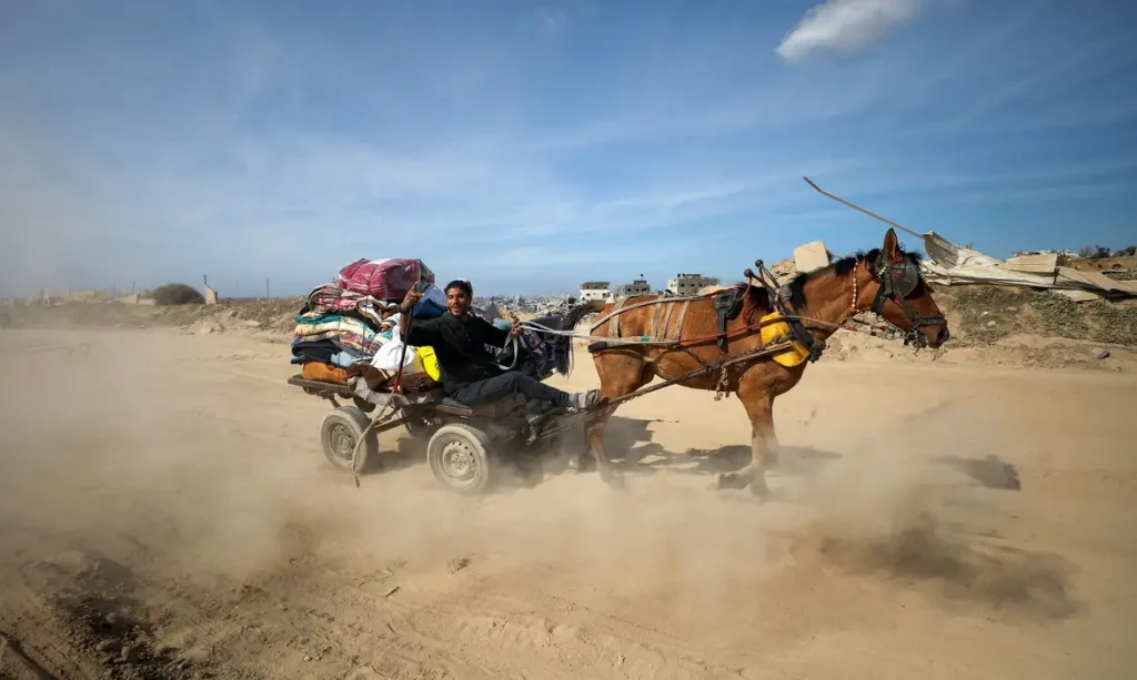 A Palestinian man reacts while riding a horse-drawn cart as he returns to his devastated neighborhood, following a ceasefire between Israel and Hamas, in Jabalia in the northern Gaza Strip, January 19, 2025. REUTERS/Dawoud Abu Alkas      TPX IMAGES OF THE DAY