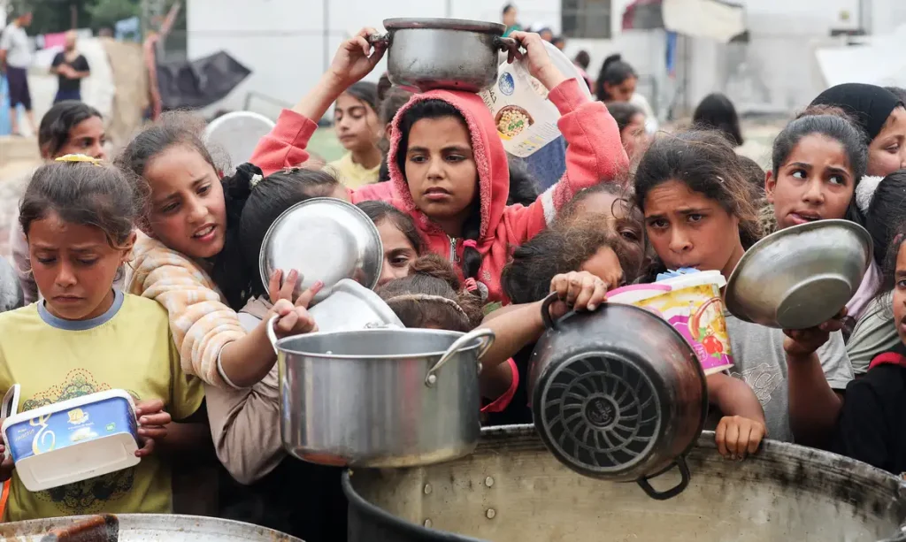 Palestinos aguardam para receber comida preparada por uma cozinha comunitária, em Nuseirat, Faixa de Gaza
08/04/2025
REUTERS/Ramadan Abed