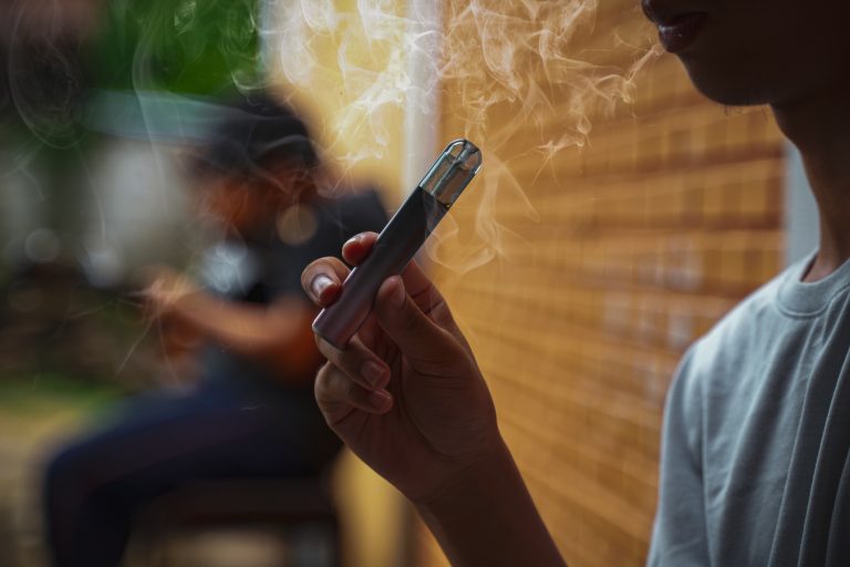 Adolescente segura um cigarro eletrônico