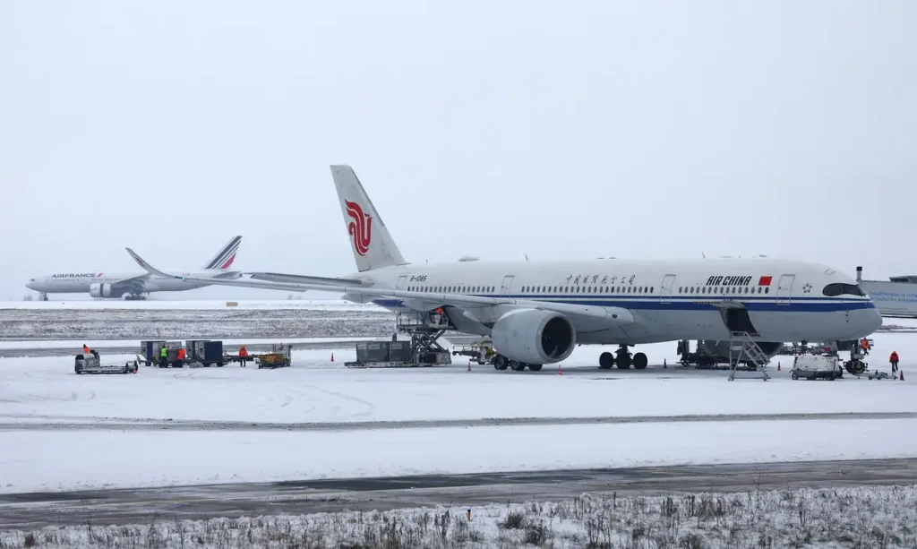 An Air China plane is seen on the snow-covered tarmac at the Paris CDG Terminal 1 of the Paris-Charles de Gaulle Airport, in Roissy-en-France, near Paris, as traffic is disrupted and some flights cancelled due winter weather with snow and cold temperatures on part of the country, France, January 7, 2026. REUTERS/Abdul Saboor