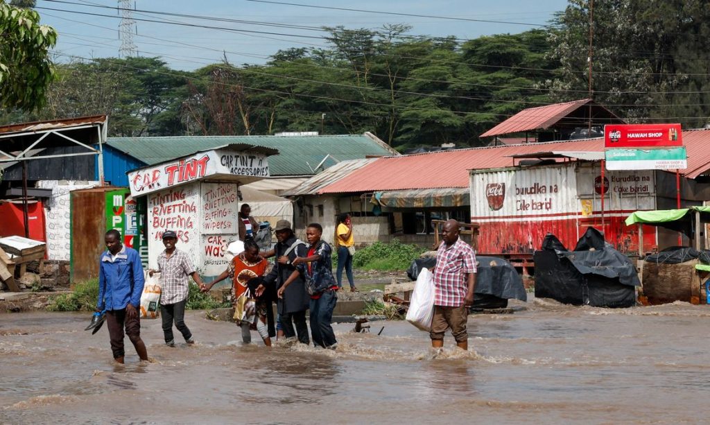 People hold hands as they walk through flood water following heavy rainfall in the Ruai area of Nairobi, Kenya, April 28, 2026. REUTERS/Monicah Mwangi