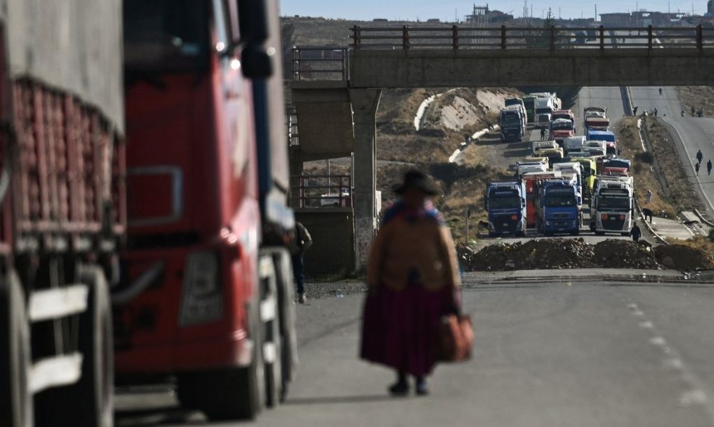 A woman walks among trucks stranded for days as protesters block a major highway, demanding the resignation of President Rodrigo Paz amid an ongoing economic and fuel crisis, in Apacheta, Bolivia, May 13, 2026. REUTERS/ Claudia Morales     TPX IMAGES OF THE DAY