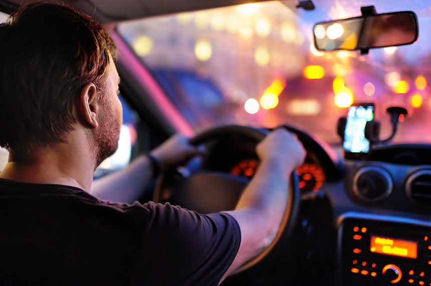 Motorista masculino dirige um carro durante o engarrafamento da noite. Vista interior.