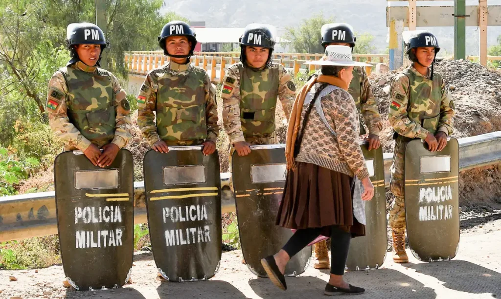 Military personnel stand in formation as they are deployed, while a woman walks past in front of them, after Bolivian President Rodrigo Paz declared a nationwide state of emergency following weeks of violence and blockades,  in Cochabamba, Bolivia, June 20, 2026. REUTERS/Patricia Pinto

     TPX IMAGES OF THE DAY