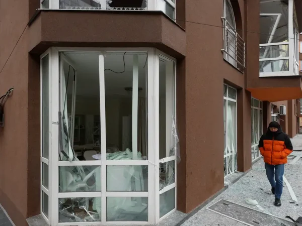 Homem anda em área de prédio residencial abalado por um ataque de drones russos a Kiev