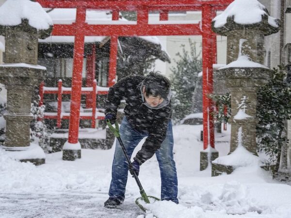 Homem limpa a neve na frente de templo em Tottori, Japão