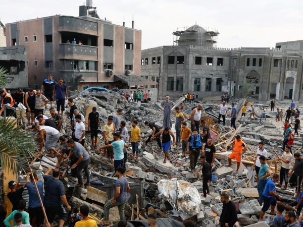 Palestinos caminham em meio a destroços de prédios em Gaza destruídos por ataques de Israel