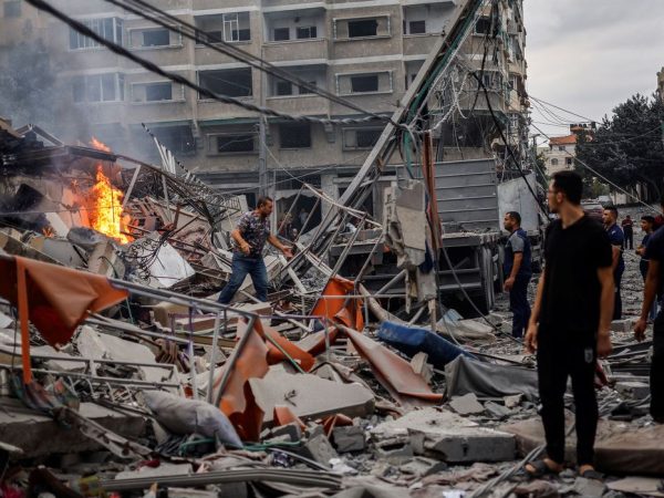 Palestinos caminham em meio a destroços de prédios destruídos por Israel em Gaza