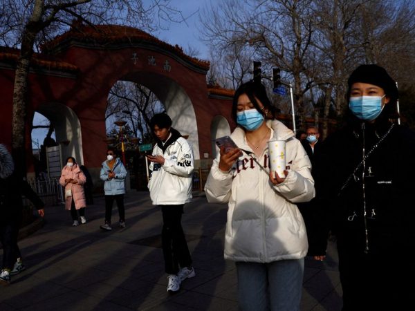 FILE PHOTO: People, wearing masks to prevent coronavirus disease (COVID-19), walk along the street in Beijing, China, February 14, 2023. REUTERS/Tingshu Wang/File Photo