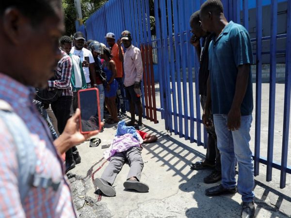 As pessoas olham para o corpo de um homem morto enquanto gangues rivais disputam o controle do território enquanto o estado permanece em grande parte ausente, em Porto Príncipe, Haiti 1º de abril de 2024. REUTERS/Ralph Tedy Erol