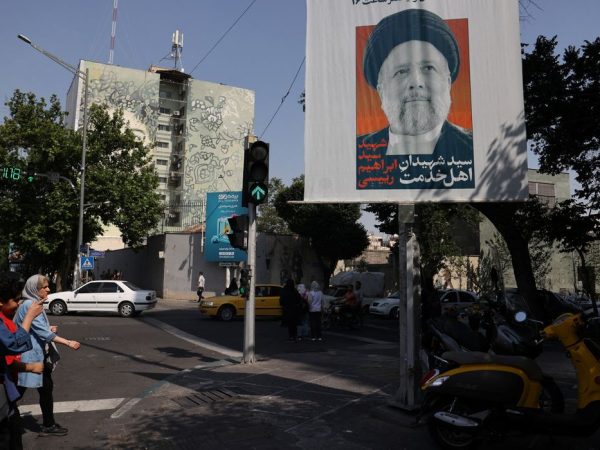 People stand near a banner with a picture of the late Iran's President Ebrahim Raisi on a street in Tehran, Iran May 20, 2024. Majid Asgaripour/WANA (West Asia News Agency) via REUTERS ATTENTION EDITORS - THIS PICTURE WAS PROVIDED BY A THIRD PARTY