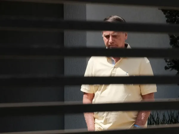 Brazil's former President Jair Bolsonaro stands at his home while under house arrest, amid the final phase of his trial, accused of plotting a coup after his electoral defeat, in Brasilia, Brazil, September 3, 2025. REUTERS/Diego Herculano   REFILE - CORRECTING DATE FROM