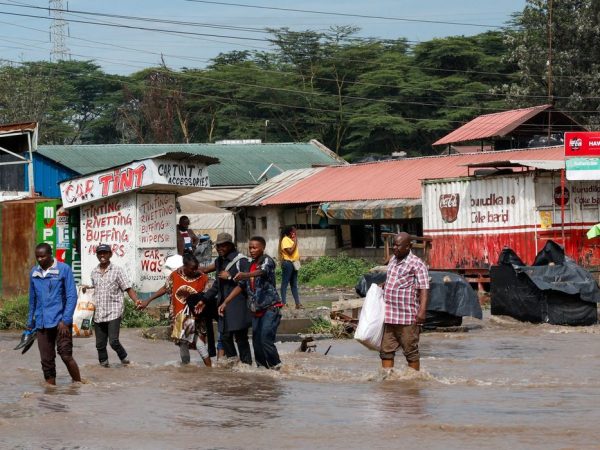 People hold hands as they walk through flood water following heavy rainfall in the Ruai area of Nairobi, Kenya, April 28, 2026. REUTERS/Monicah Mwangi