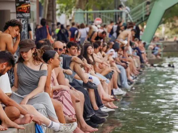 People sit along the Canal Saint-Martin to find some relief from the heat as public swimming having been allowed earlier on part of it due to rising of temperatures, in Paris as a heatwave hits a large of France, June 18, 2026. REUTERS/Alice Sacco