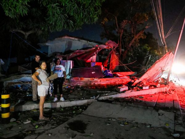 People stand next to a destroyed building after earthquakes, in La Guaira, Venezuela, June 25, 2026. REUTERS/Maxwell Briceno