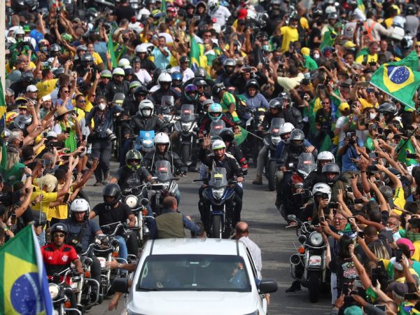 O presidente Jair Bolsonaro (ao centro) faz passeio de moto com aglomeração neste domingo (23) — Foto: Pilar Olivares/Reuters