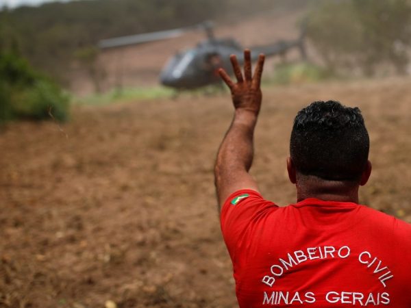 Bombeiro gesticula perto de um helicóptero de resgate dois dias depois do rompimento da barragem da Vale em Brumadinho. — Foto: Adriano Machado/Reuters