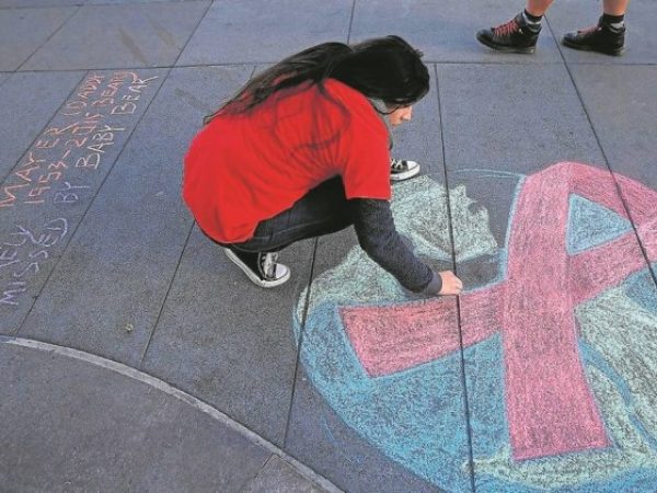 Mulher da Califórnia, nos EUA, desenha o símbolo da luta contra a AIDS - Justin Sullivan/AFP