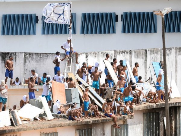 Presidiários se reúnem no telhado durante rebelião no Centro Penitenciário de Alcaçuz, perto de Natal (RN), para evitar confronto com facções. No  fim de semana, 26 detentos do presídio morreram em uma rebelião que durou mais de 14 horas — Foto: Andressa Anholete/AFP