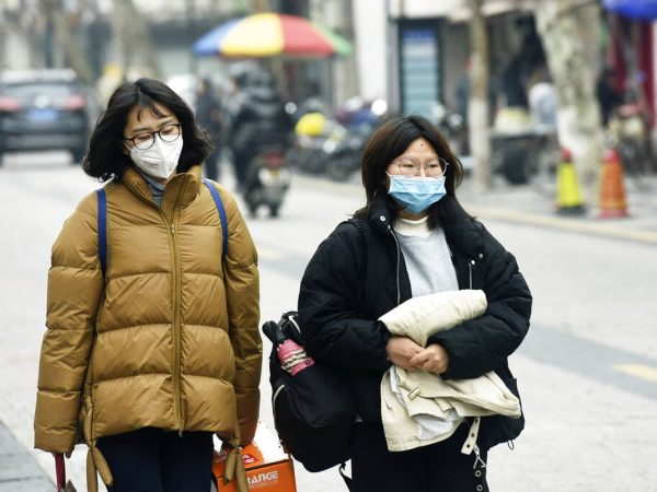 Mulheres usam máscaras enquanto andam por uma rua em Hangzhou, na província de Zhejiang, leste da China — Foto: Chinatopix/AP