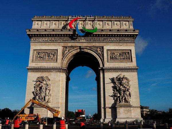 Workers stand next to the Arc de Triomphe with the Paralympic Games symbol attached to it, ahead of the Paris 2024 Olympic and Paralympic Games, in Paris, France, June 28, 2024. REUTERS/Gonzalo Fuentes
