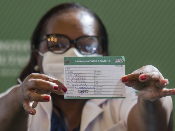 Mônica Calazans mostra seu cartão de vacinação após ser a primeira brasileira a receber a vacina CoronaVac — Foto: Carla Carniel/AP