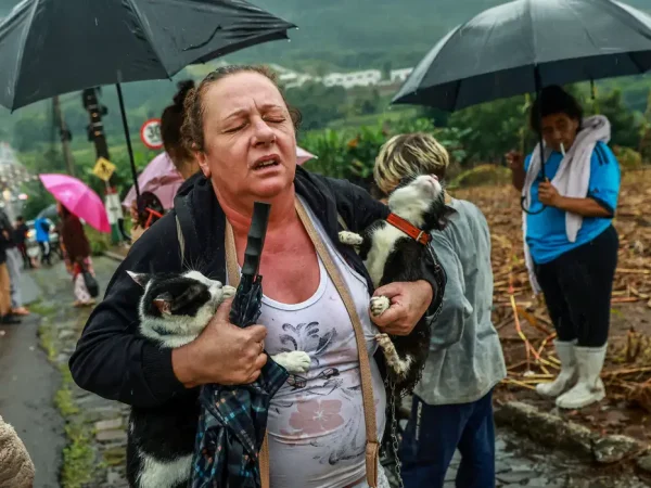 A woman reacts as she walks with two rescued cats during heavy rains in Encantado, Rio Grande do Sul state, Brazil, May 2, 2024. REUTERS/Diego Vara