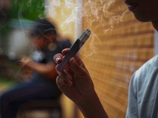 Adolescente segura um cigarro eletrônico