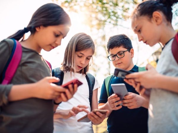 Crianças reunidas mexendo no celular