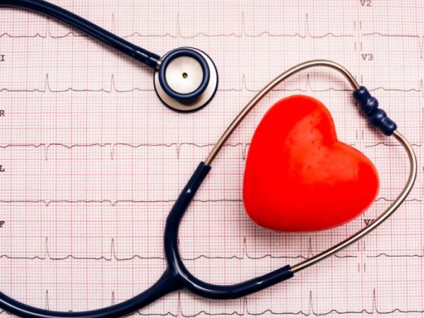 Imagem mostra estetoscópio e bolinha de massagem em formato de coração em cima de um eletrocardiograma