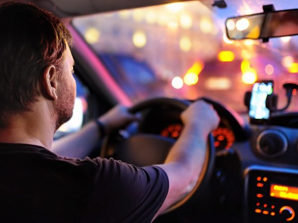 Motorista masculino dirige um carro durante o engarrafamento da noite. Vista interior.