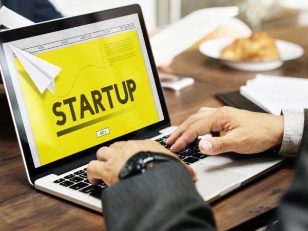 Pessoa digita num laptop onde se lê: startup
