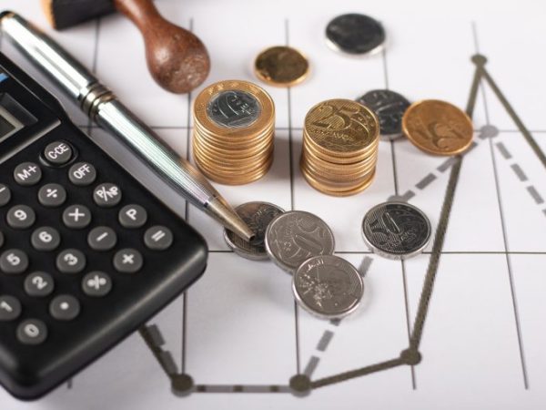 Gráficos com moedas, uma calculadora e um caneta em cima