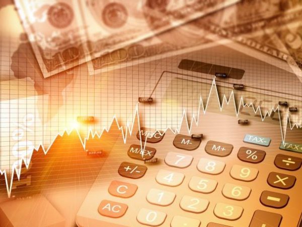 Imagem de uma calculadora com notas de dinheiro e gráficos em cima