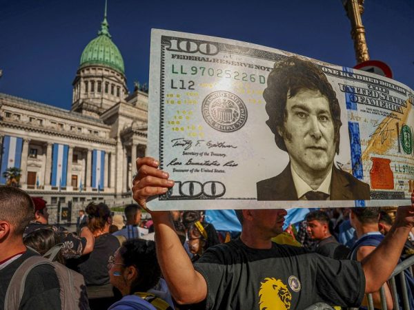 A supporter of Argentina's President-elect Javier Milei holds up a representation of a 100 dollar bill featuring an image of c on the day of his swearing-in ceremony, outside the National Congress, in Buenos Aires, Argentina December 10, 2023. REUTERS/Agustin Marcarian