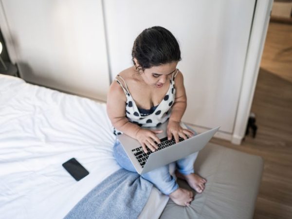 Pessoa com nanismo em casa usando computador