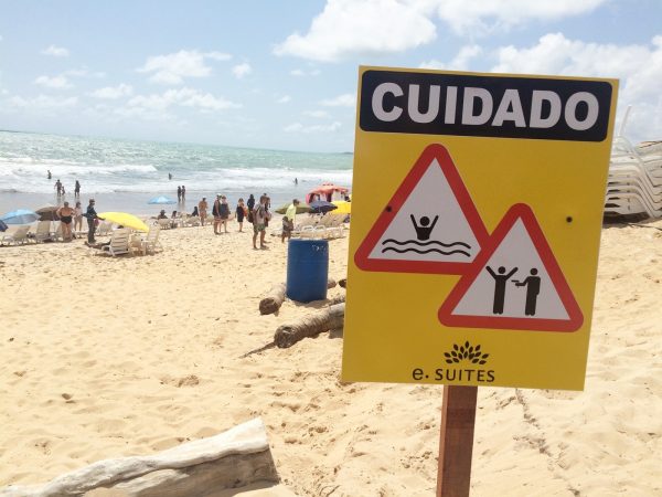Na areia da praia, hotel fincou placas para alertar os hóspedes. É preciso atenção com os riscos de afogamento e de assaltos (Foto: Anderson Barbosa/G1)