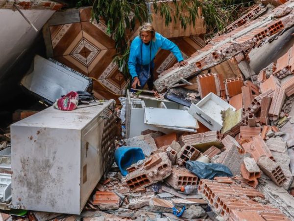Uma pessoa está no meio de escombros de uma casa destruída pelas chuvas