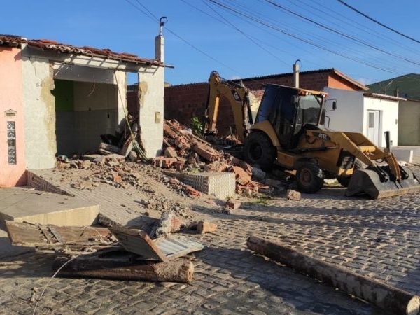 Retroescavadeira derruba muro durante operação em Mossoró, na manhã desta segunda-feira (25). No chão, canos que reforçavam o portão do local — Foto: Isaiana Santos/Inter TV Costa Branca