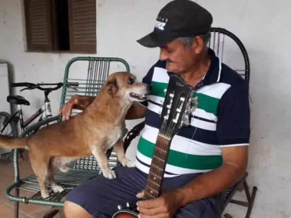 Pedreiro Alcides Soares, de 57 anos, comemora resgate do cachorro Quinho de incêndio que destruiu a casa onde eles moravam, em Natal — Foto: Klênyo Galvão/Inter TV Cabugi