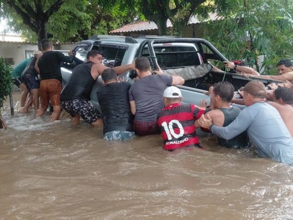 Homens ajudam a empurrar caminhonete que ficou boiando durante alagamento — Foto: Reprodução